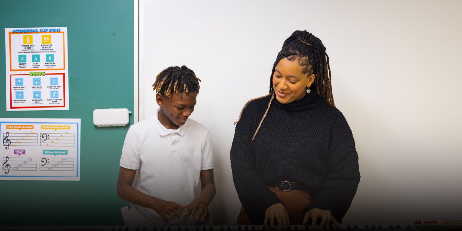 A teacher playing piano with a student