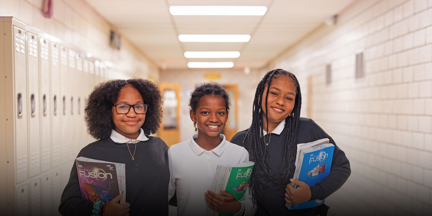 Students smiling in the hallway with books